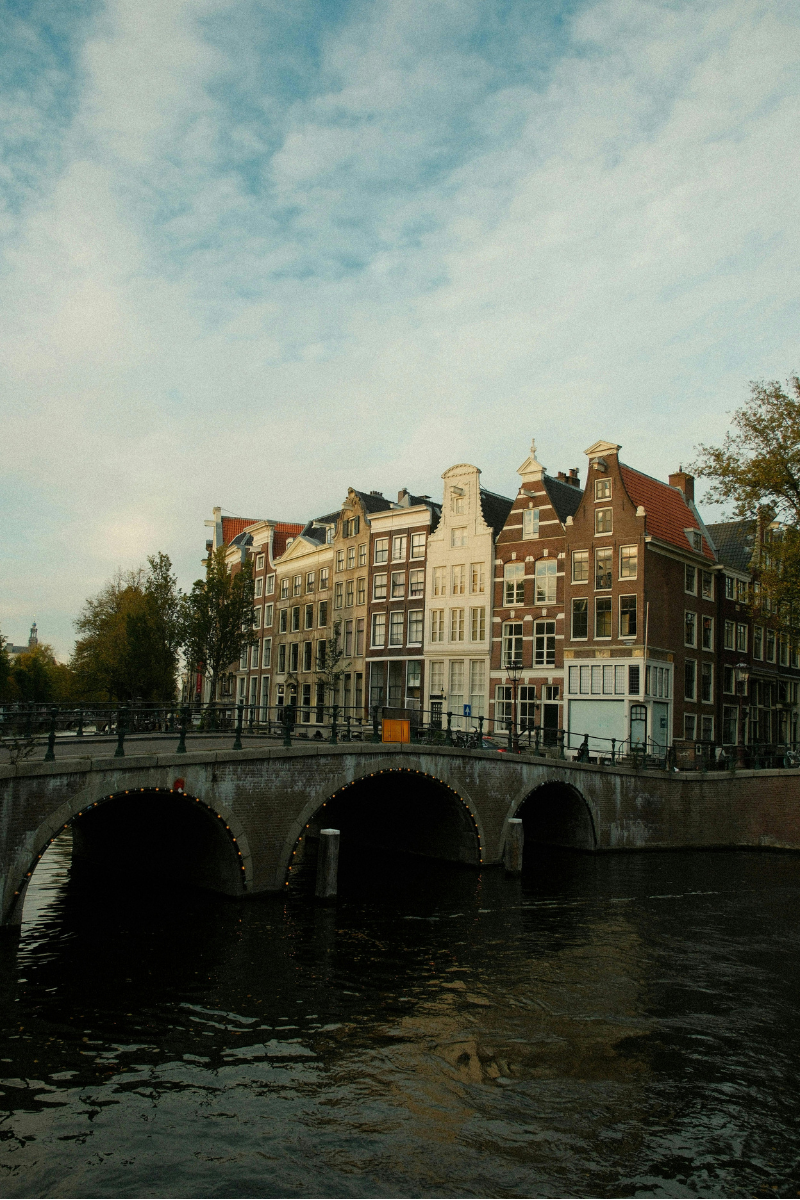 Hidden Amsterdam spots - golden hour sunset over quiet canal with reflections of historic buildings